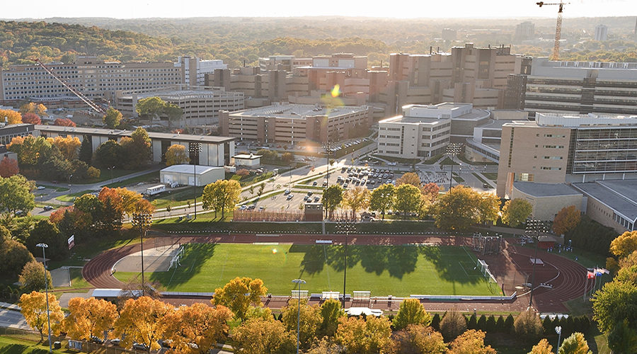 Major campus facilities pictured from counterclockwise from bottom include the UW Marching Band practice field, McClimon Complex (track and soccer field), Rennebohm Hall, Health Sciences Learning Center, Wisconsin Institutes for Medical Research, UW Hospital and Clinics, Veterans Administration Hospital, and WARF Office Building. The photograph was made from a helicopter looking southwest.