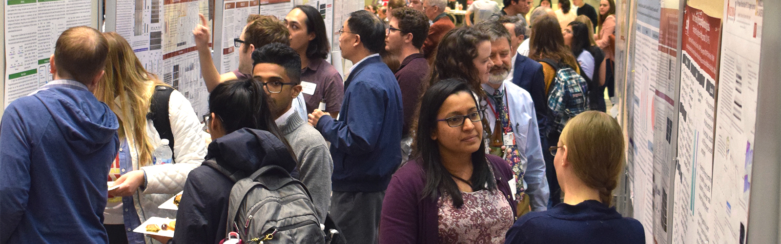 Attendees of the 2019 UWCCC Research Retreat participate in the scientific poster sessions, crowding between rows of poster boards.