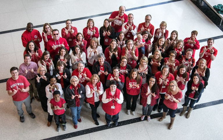UW staff dressed in red holding up their hands in the shape of a W