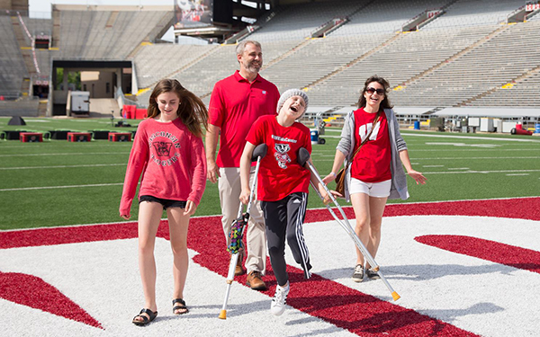 A patient skips down the field joyfull at Camp Randal with their family.