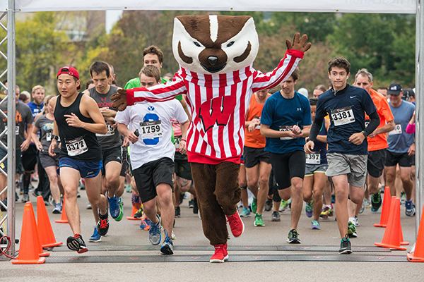 Bucky crossing the starting line at Race for Research, followed by other racers.